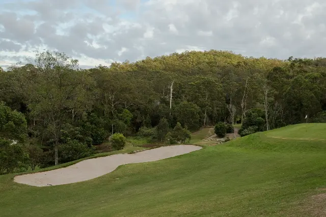 The photograph: a long pale bunker curving through the fairway at Ashgrove, gum trees on a hillside behind.