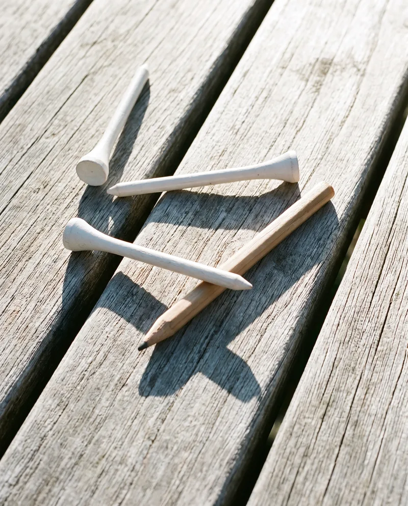 Wooden tees and a scorecard pencil on a weathered bench.